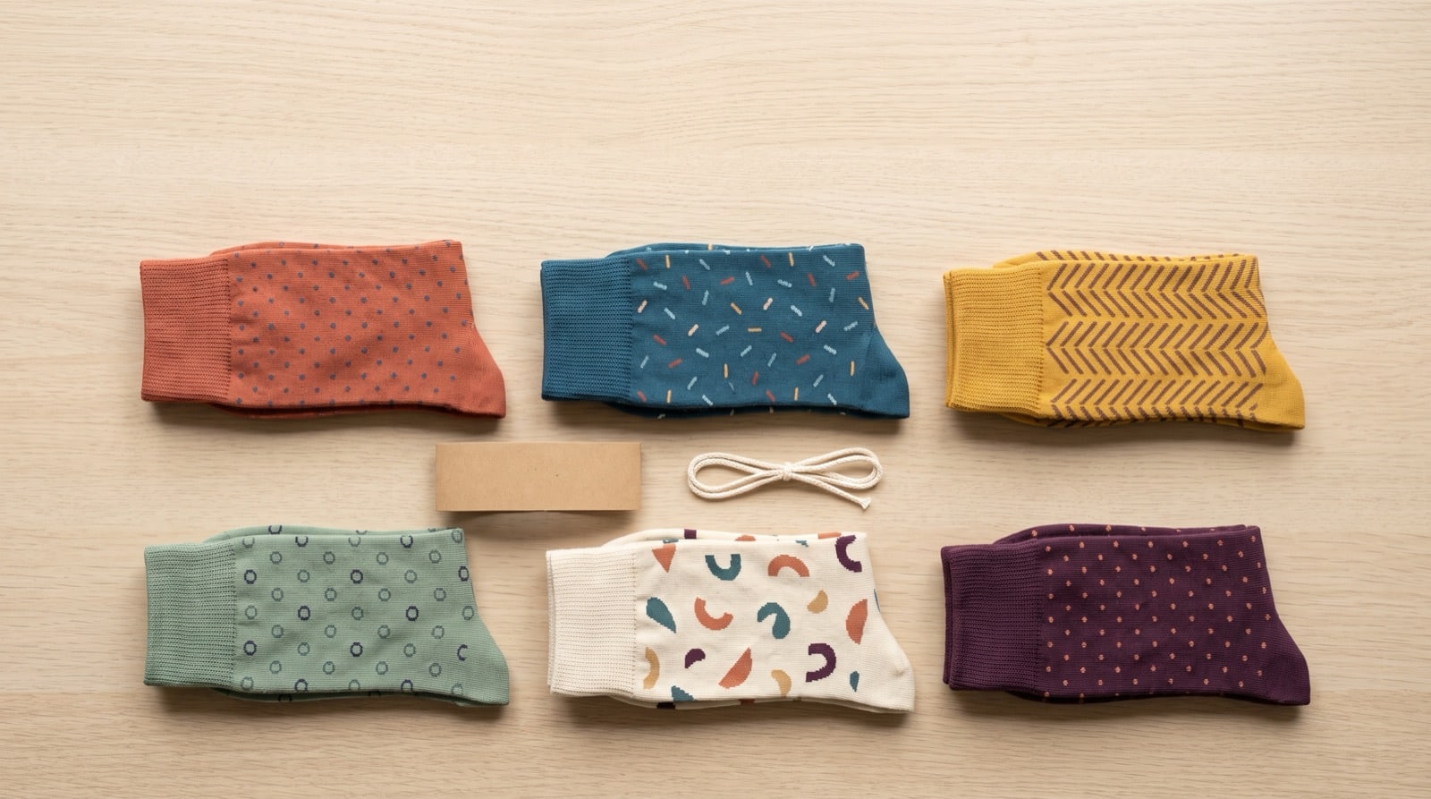 Six paires de chaussettes à motifs pliées et alignées, vue du dessus, prêtes à offrir