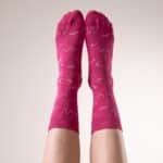 Chaussettes Octobre Rose portées, jambes levées contre un mur